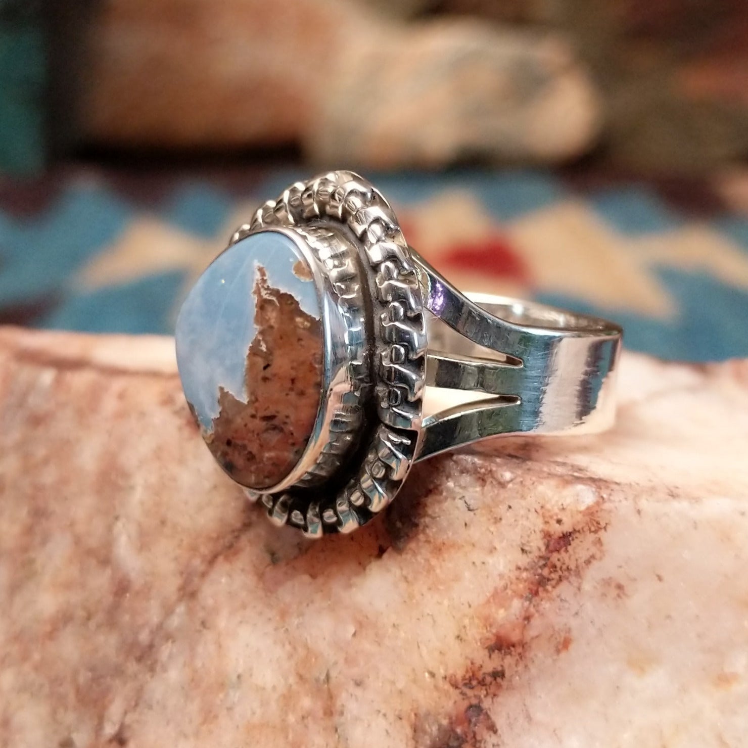 Sterling silver ring with Arizona blue opal set in the bezel, framed by the ornate setting and features vibrant green and red firing.