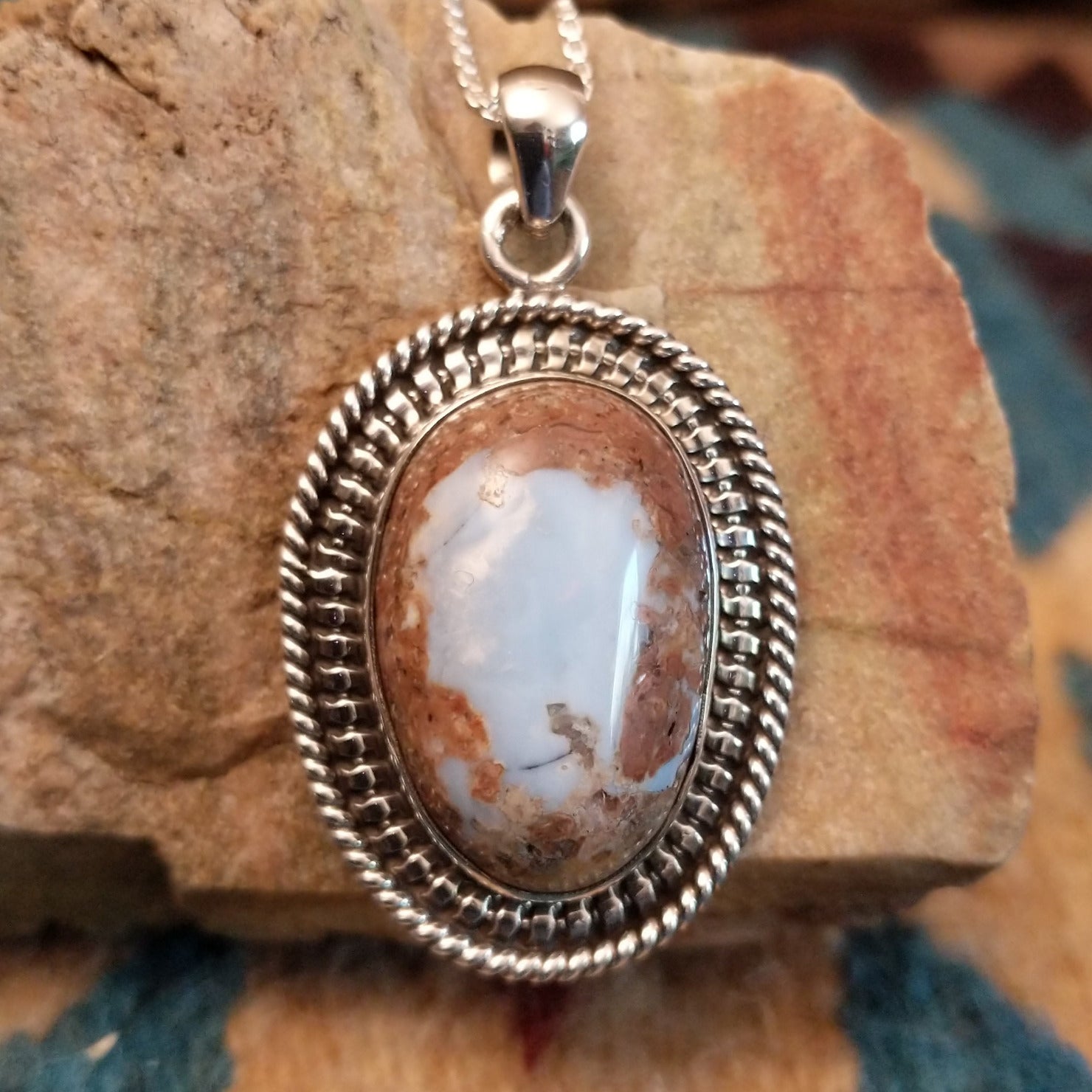 Sterling silver pendant with Arizona blue opal set in the oval bezel, framed by ornate silverwork.