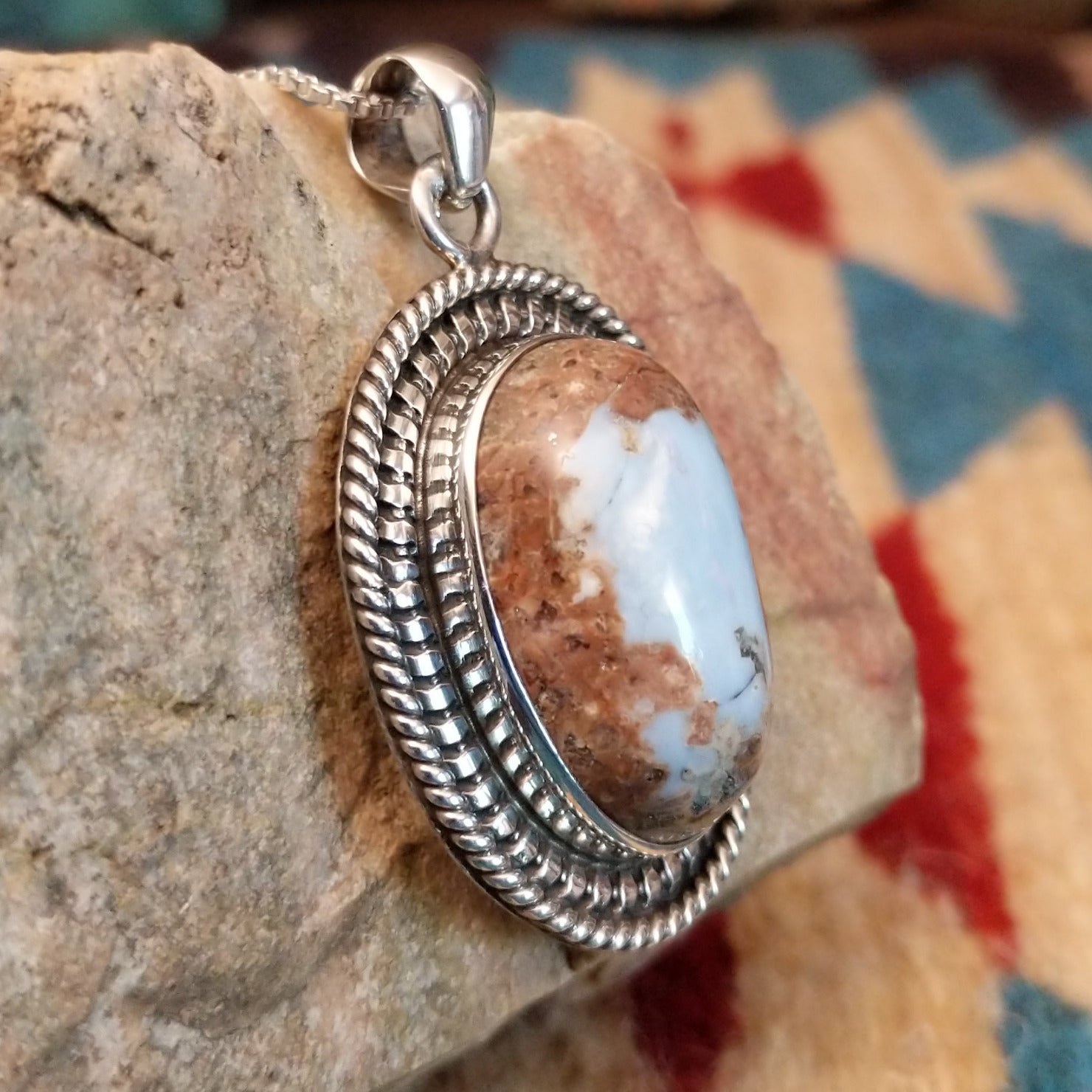 Sterling silver pendant with Arizona blue opal set in the oval bezel, framed by ornate silverwork.
