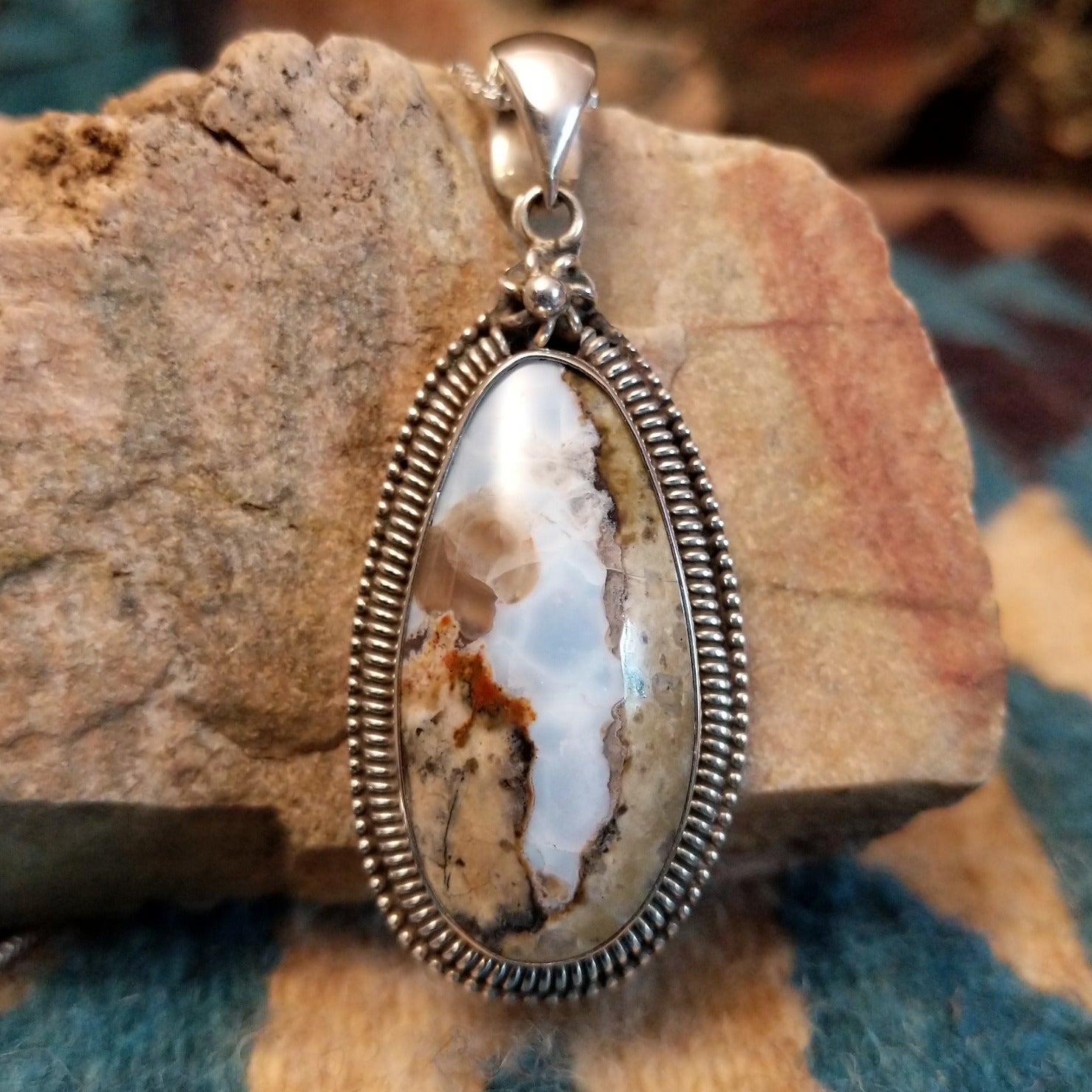 Sterling silver pendant with Arizona blue opal set in the bezel, framed by ornate silverwork accents.