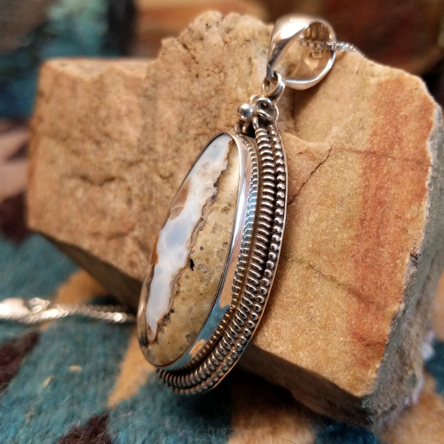 Sterling silver pendant with Arizona blue opal set in the bezel, framed by ornate silverwork accents.