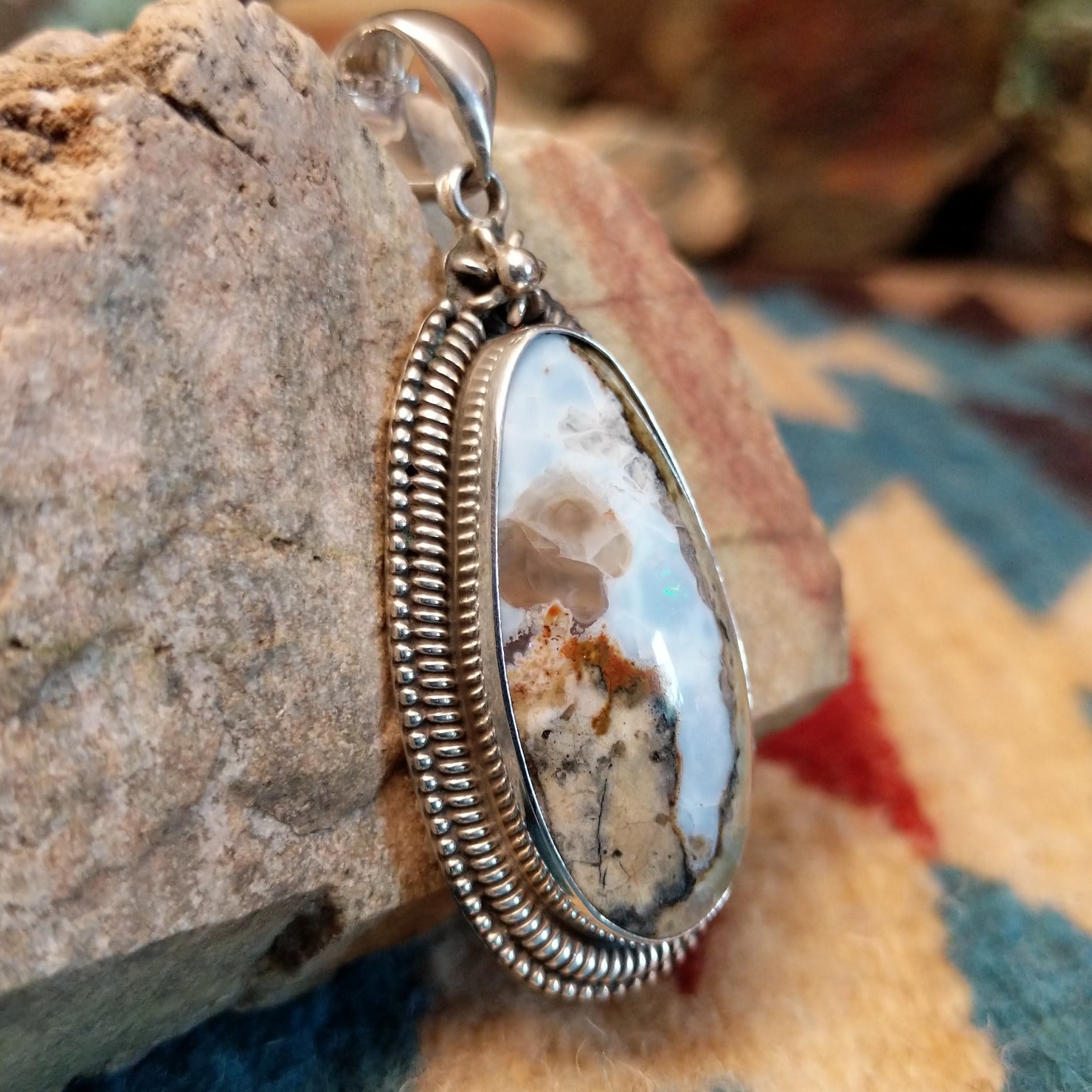 Sterling silver pendant with Arizona blue opal set in the bezel, framed by ornate silverwork accents.