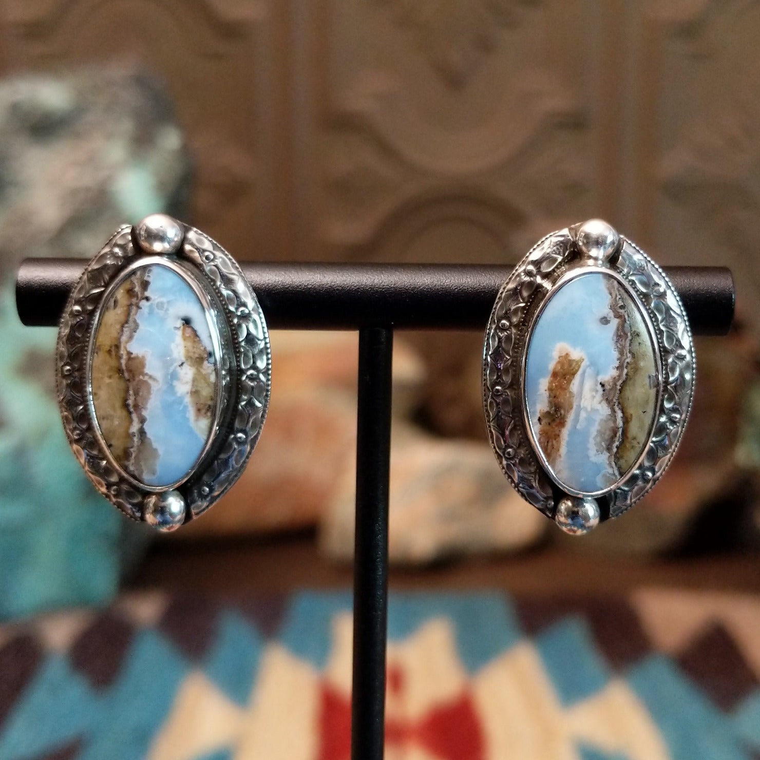 Sterling silver earrings with Arizona blue opal set in oval bezels, framed by ornate silverwork.