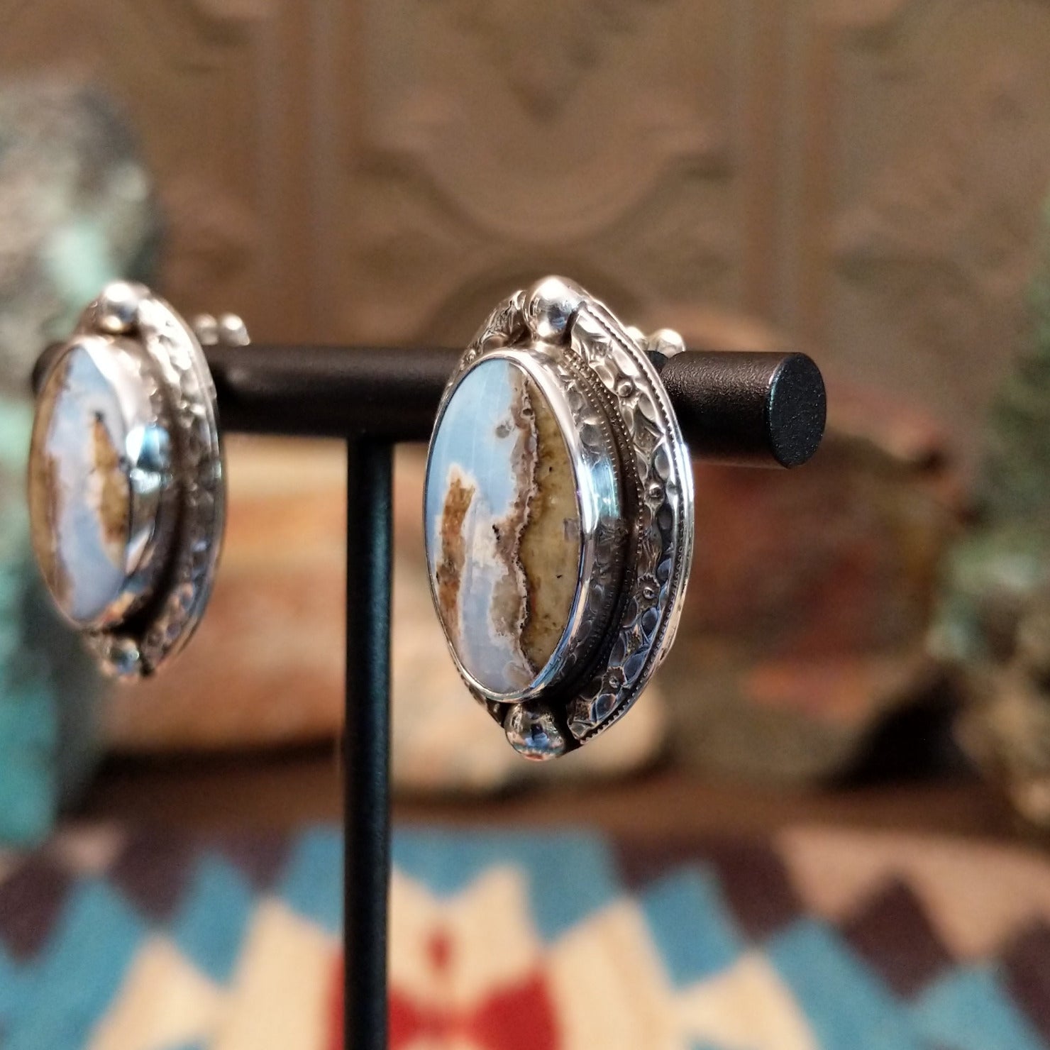 Sterling silver earrings with Arizona blue opal set in oval bezels, framed by ornate silverwork.