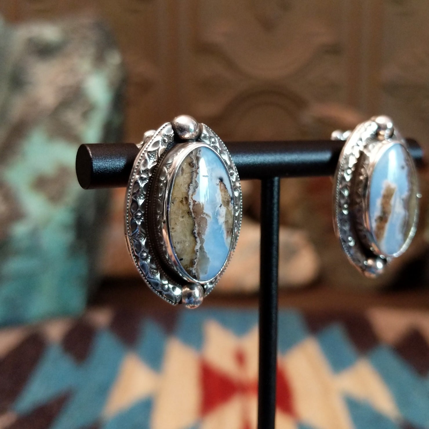 Sterling silver earrings with Arizona blue opal set in oval bezels, framed by ornate silverwork.