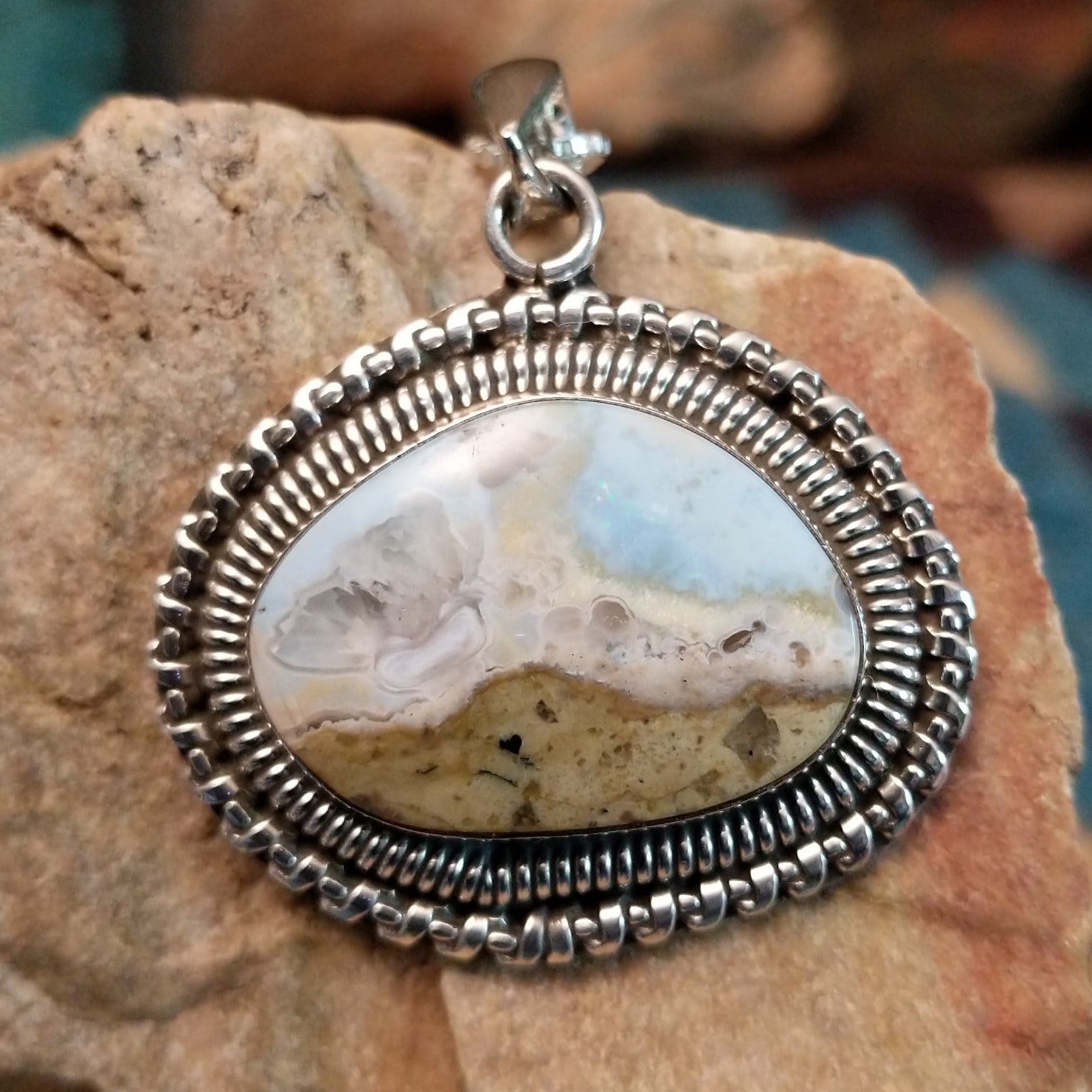 Sterling silver pendant with Arizona blue opal set in the bezel, framed by ornate silverwork accents.