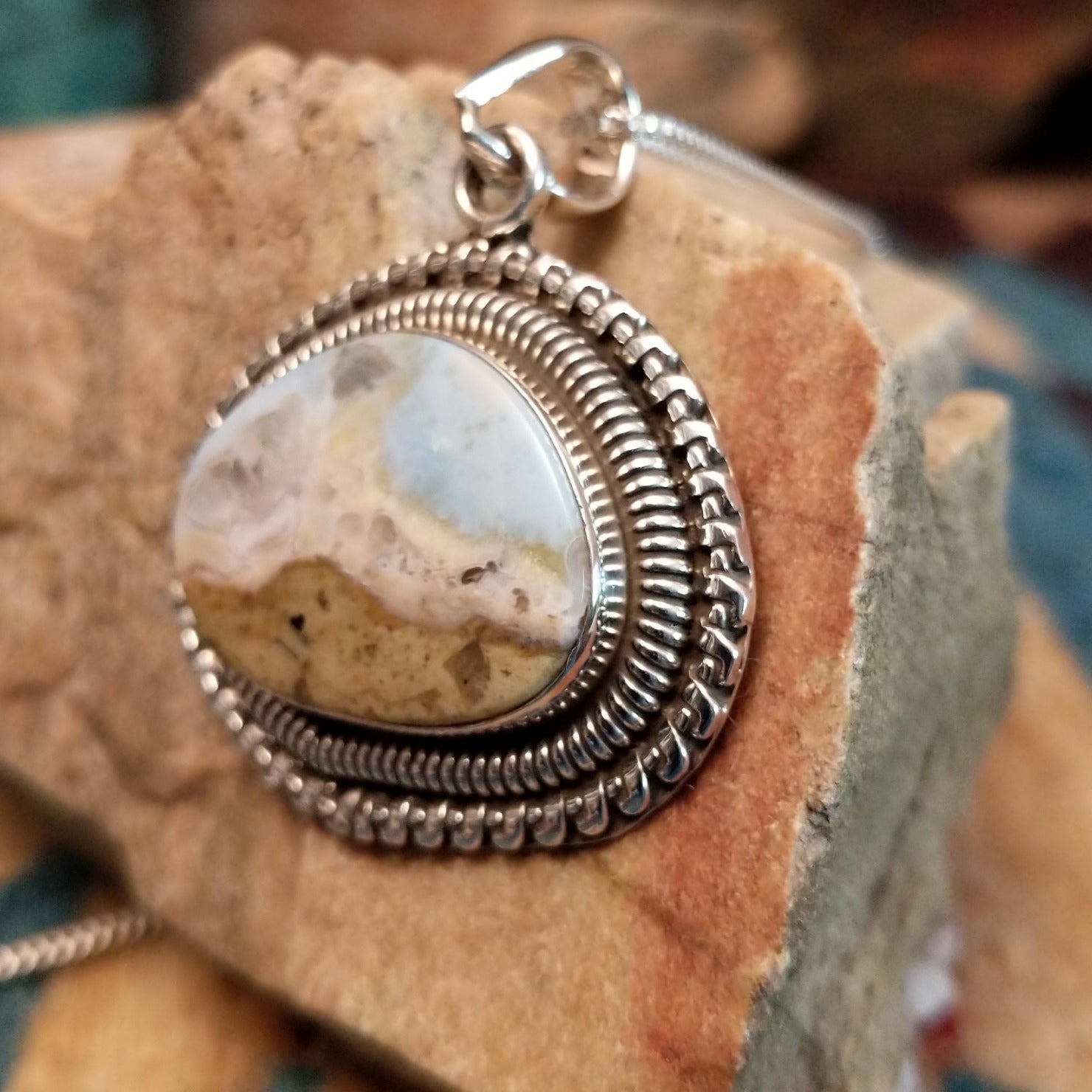 Sterling silver pendant with Arizona blue opal set in the bezel, framed by ornate silverwork accents.