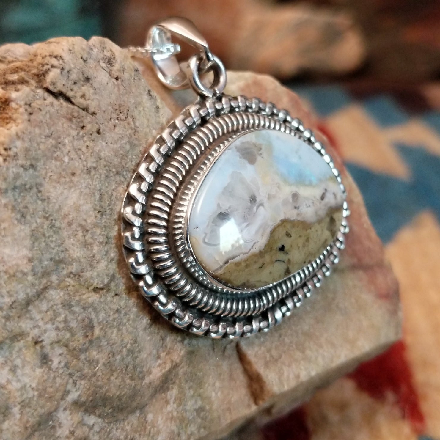 Sterling silver pendant with Arizona blue opal set in the bezel, framed by ornate silverwork accents.