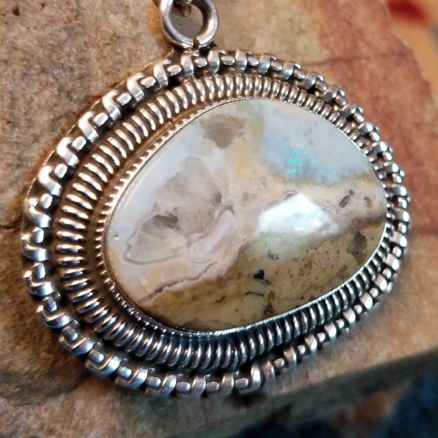 Sterling silver pendant with Arizona blue opal set in the bezel, framed by ornate silverwork accents.