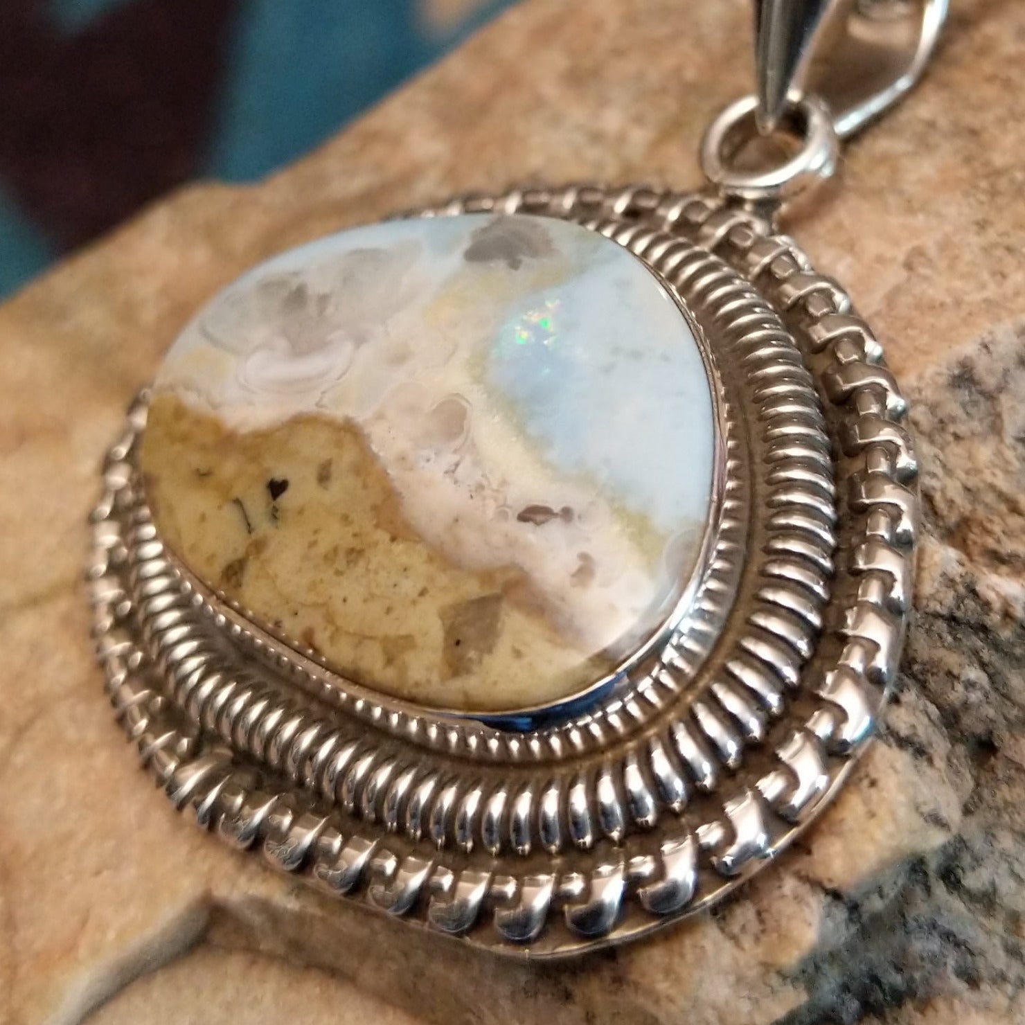 Sterling silver pendant with Arizona blue opal set in the bezel, framed by ornate silverwork accents.
