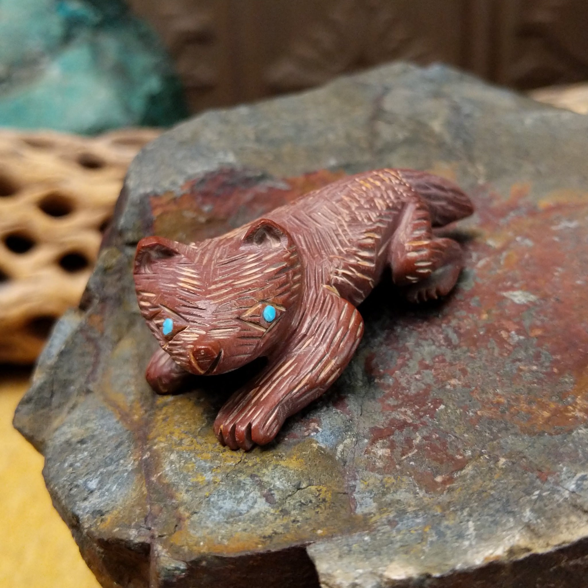 Badger Zuni fetish carving by Karen Zunie in reddish stone with etched fur and turquoise inlaid eyes.