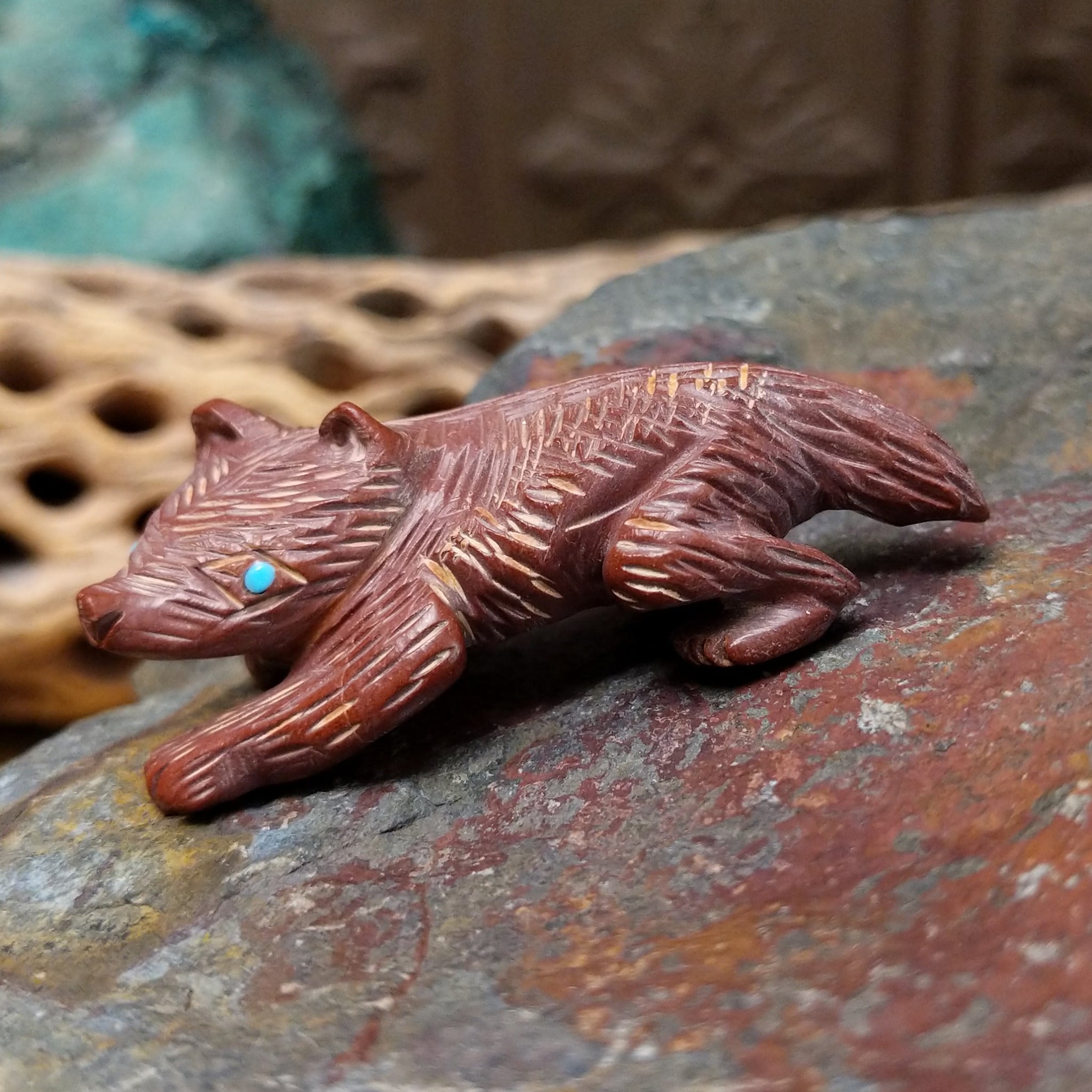 Badger Zuni fetish carving by Karen Zunie in reddish stone with etched fur and turquoise inlaid eyes.