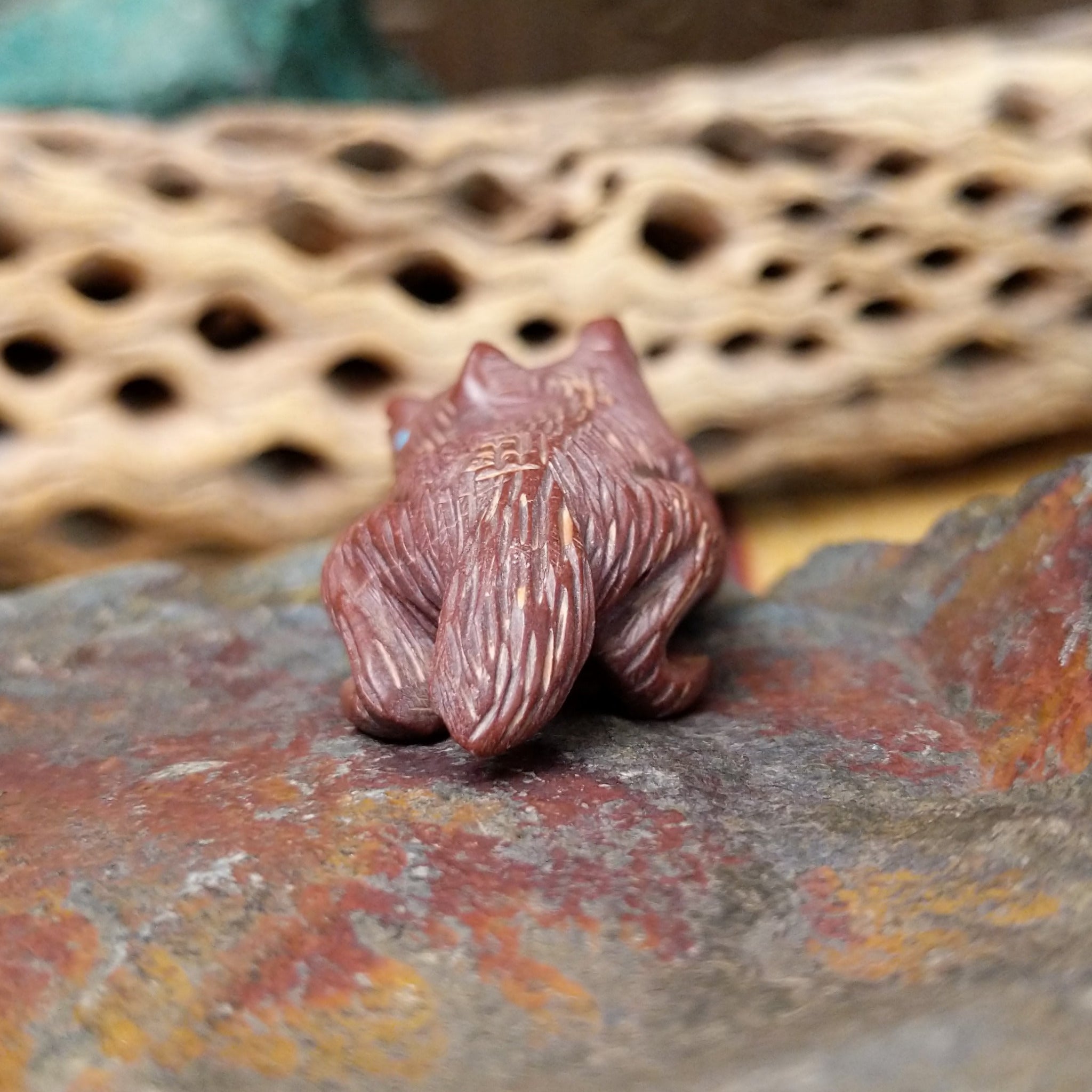 Badger Zuni fetish carving by Karen Zunie in reddish stone with etched fur and turquoise inlaid eyes.