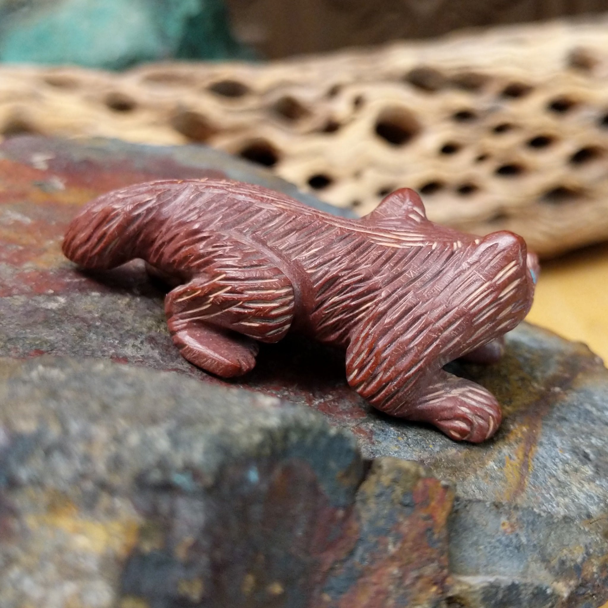Badger Zuni fetish carving by Karen Zunie in reddish stone with etched fur and turquoise inlaid eyes.