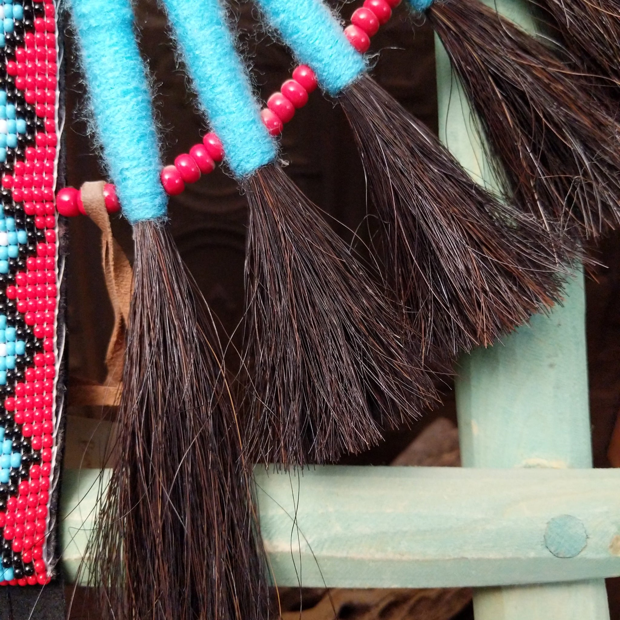 Blue Navajo Bustle artifact reproduction by Linda Lee with beadwork by Dorothy Manning, featuring turquoise, red, black, and white beadwork with dark horsehair accents.