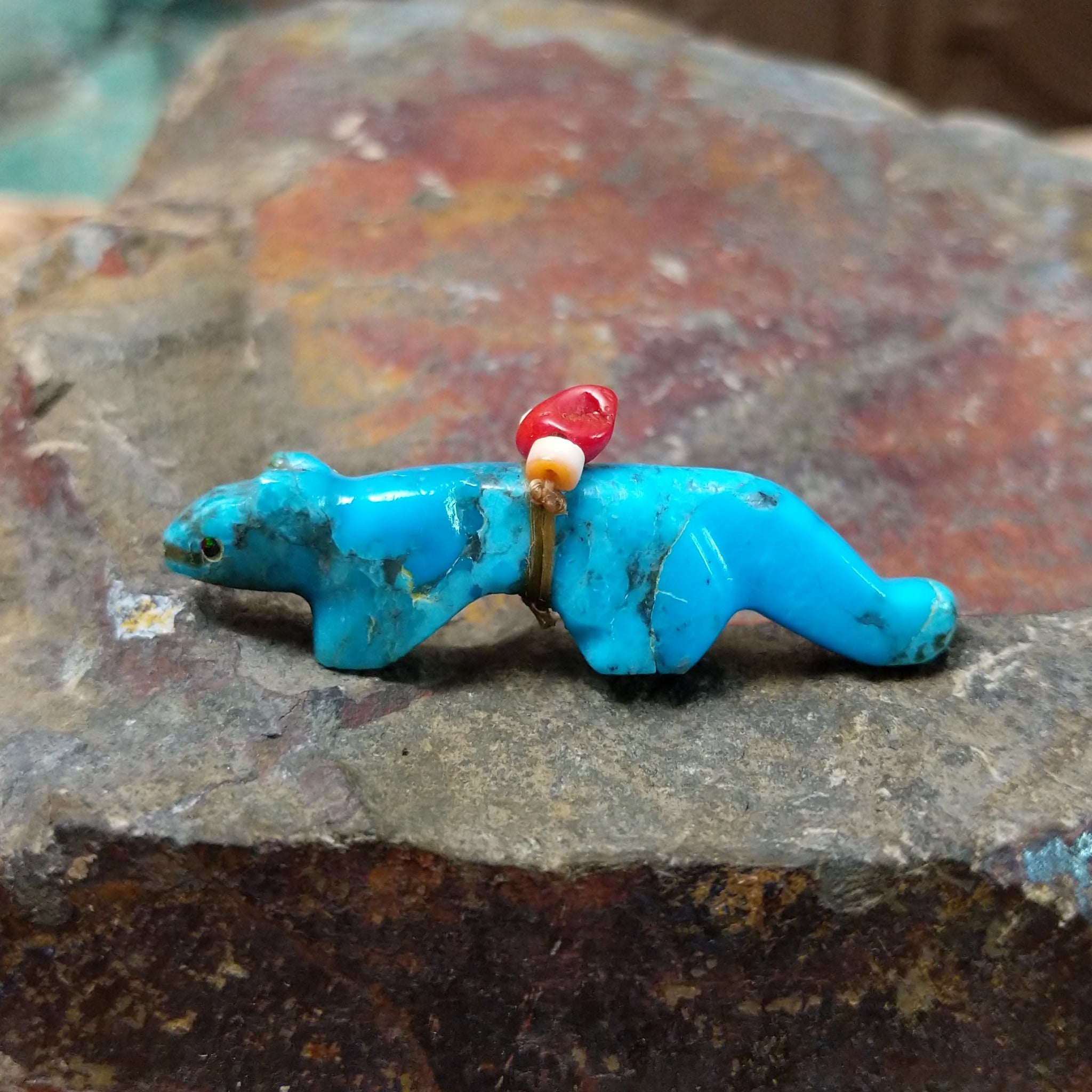 Cougar Zuni fetish by LaVies Natewa carved from turquoise with a medicine bundle on its back.