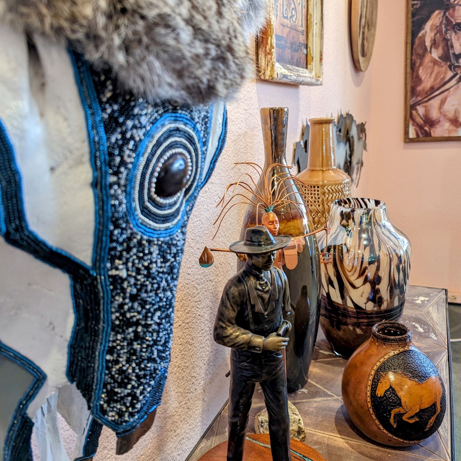 Collection of beautiful sculptures, pottery, vases and colorful artwork on the contrasting wall.