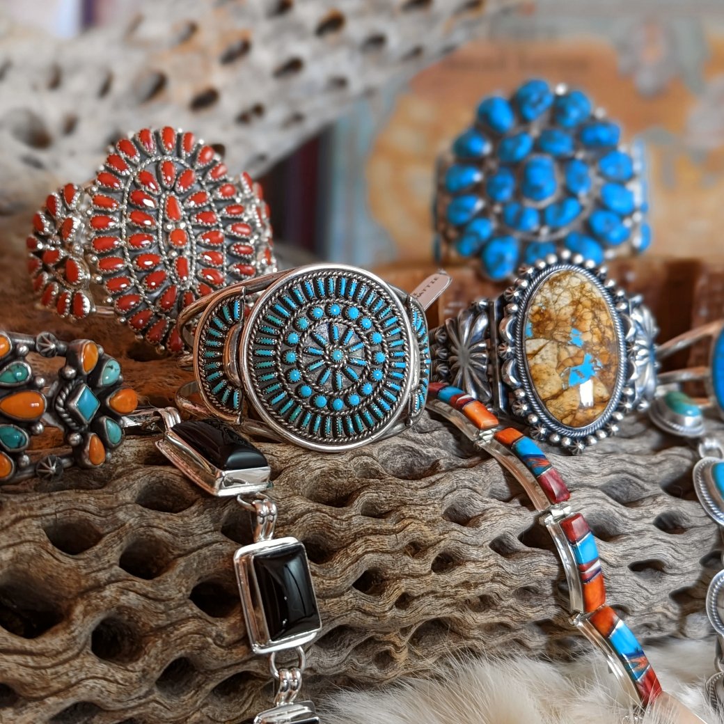 Collection of Native American jewelry in vibrant colors featuring various stones sat upon a log.