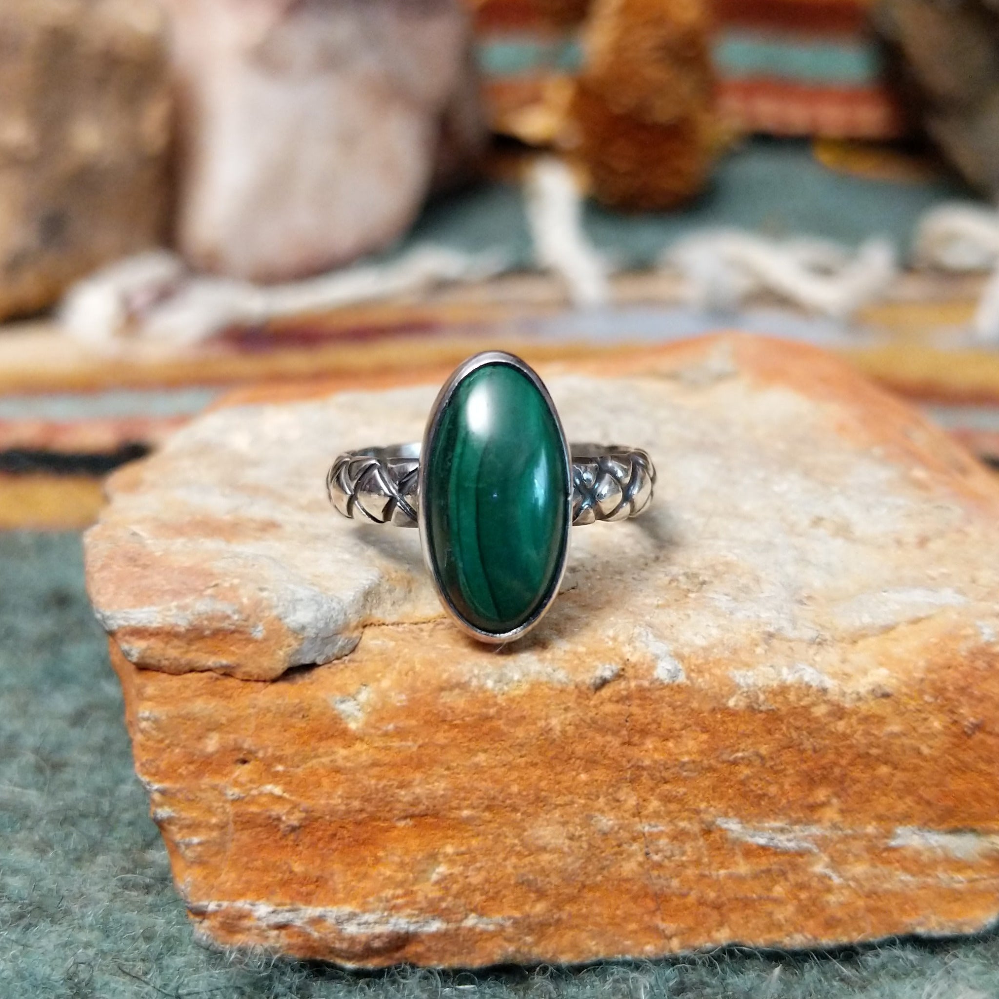 Raymond Coriz sterling silver ring featuring an elongated oval green malachite cabochon with natural dark banding and a textured knurled silver band.