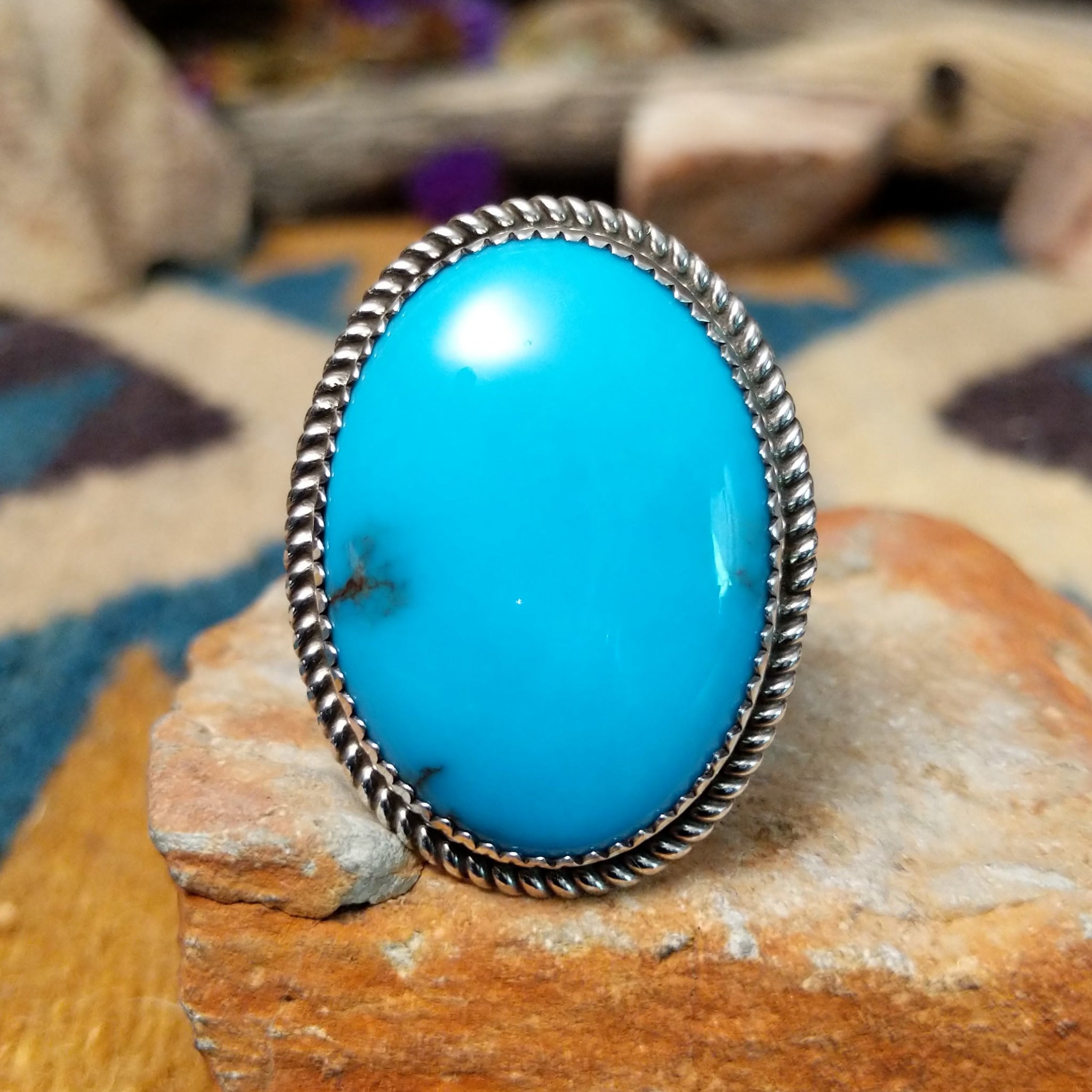 Handcrafted sterling silver Navajo ring by Alvin Joe featuring a large oval natural turquoise cabochon with subtle matrix, set in a classic twisted rope bezel.