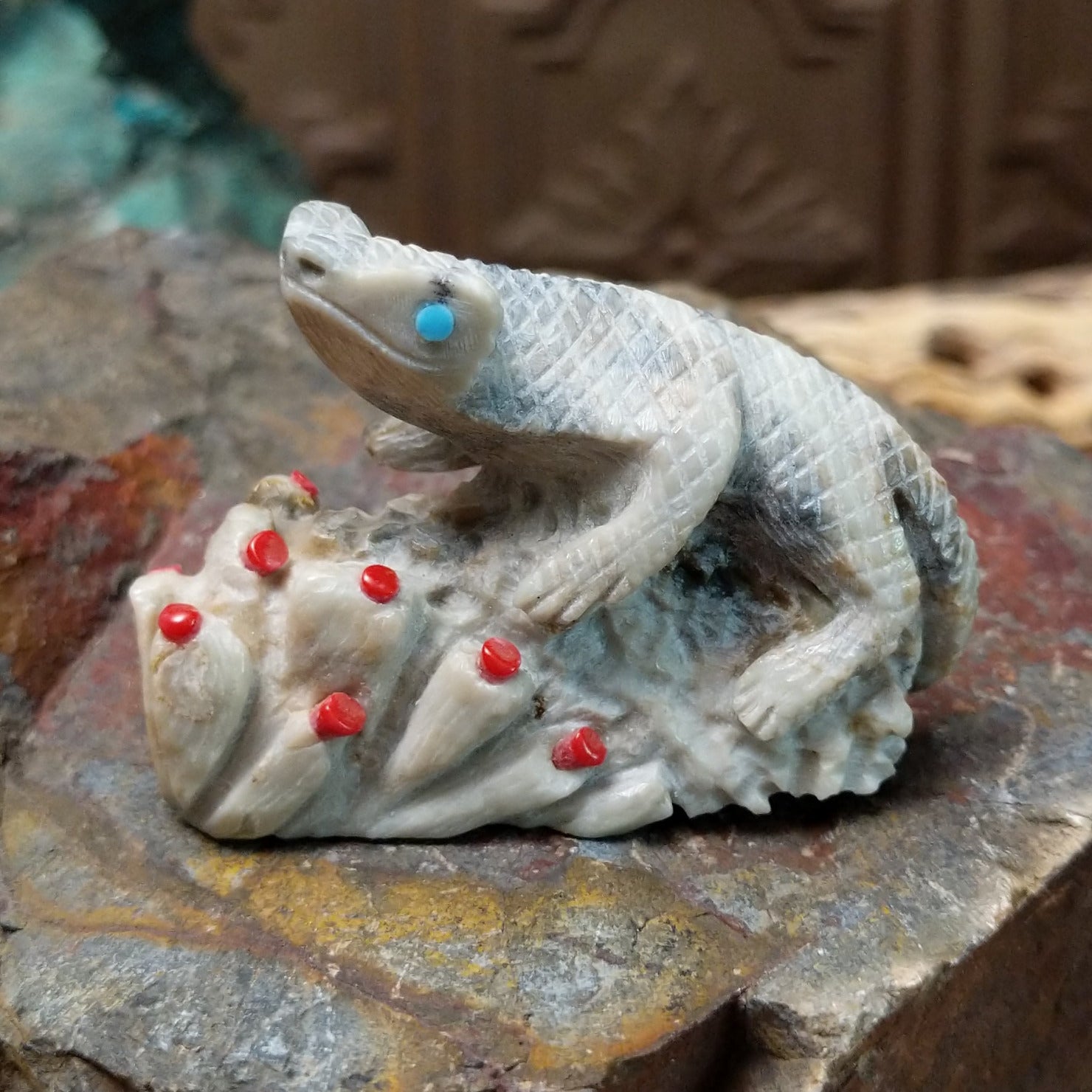 Lizard and prickly pear Zuni fetish carving by Alvin Haloo with turquoise inlaid eyes and red prickly pear fruit accents.