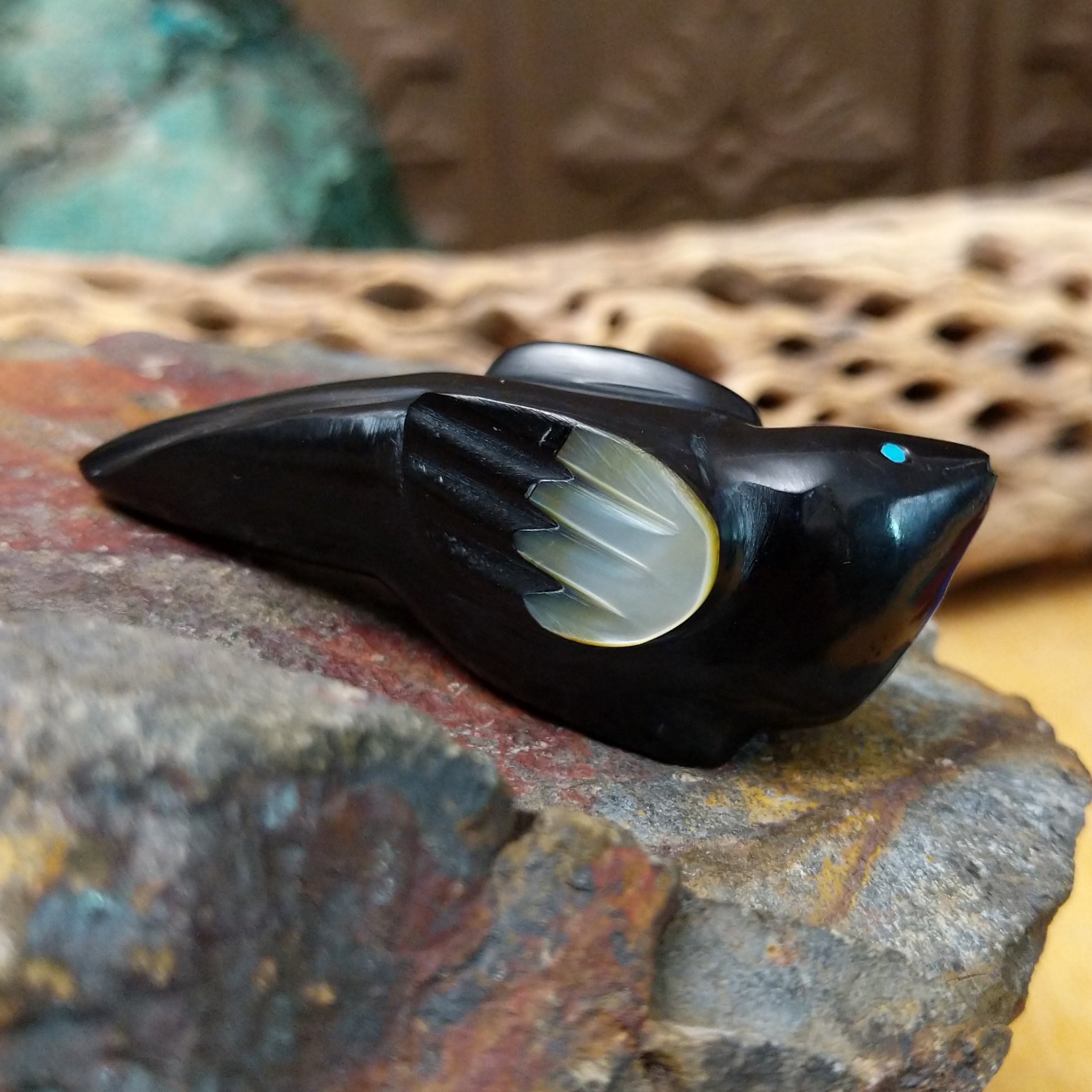 Magpie Zuni fetish carving by Delvin Leekya in black stone with shell wing inlay and turquoise eye.