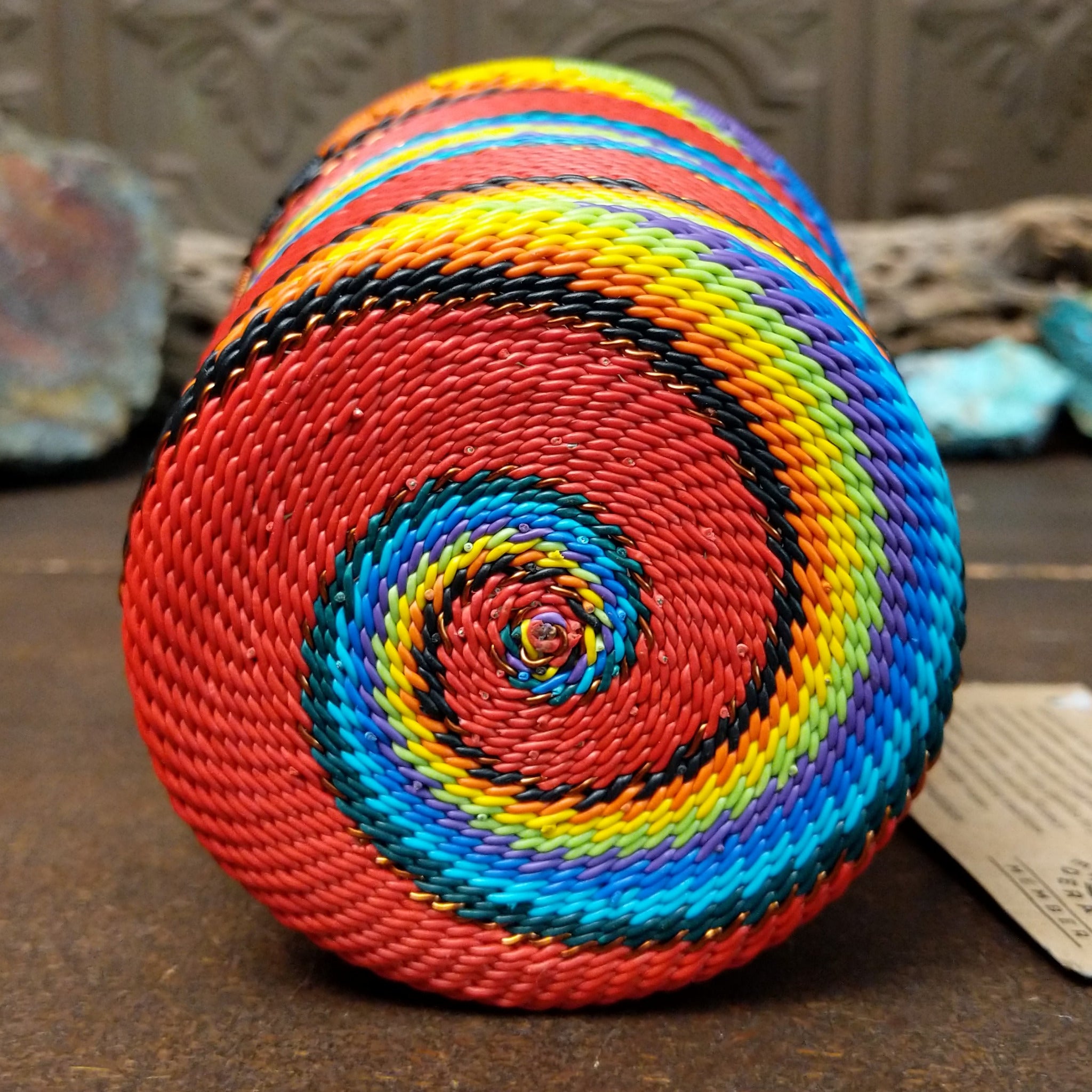 Handwoven multicolor wire art cup by Bridge for Africa featuring vibrant recycled wire in a colorful diagonal pattern, ideal as a decorative container, utensil holder, or pencil cup; underside view.