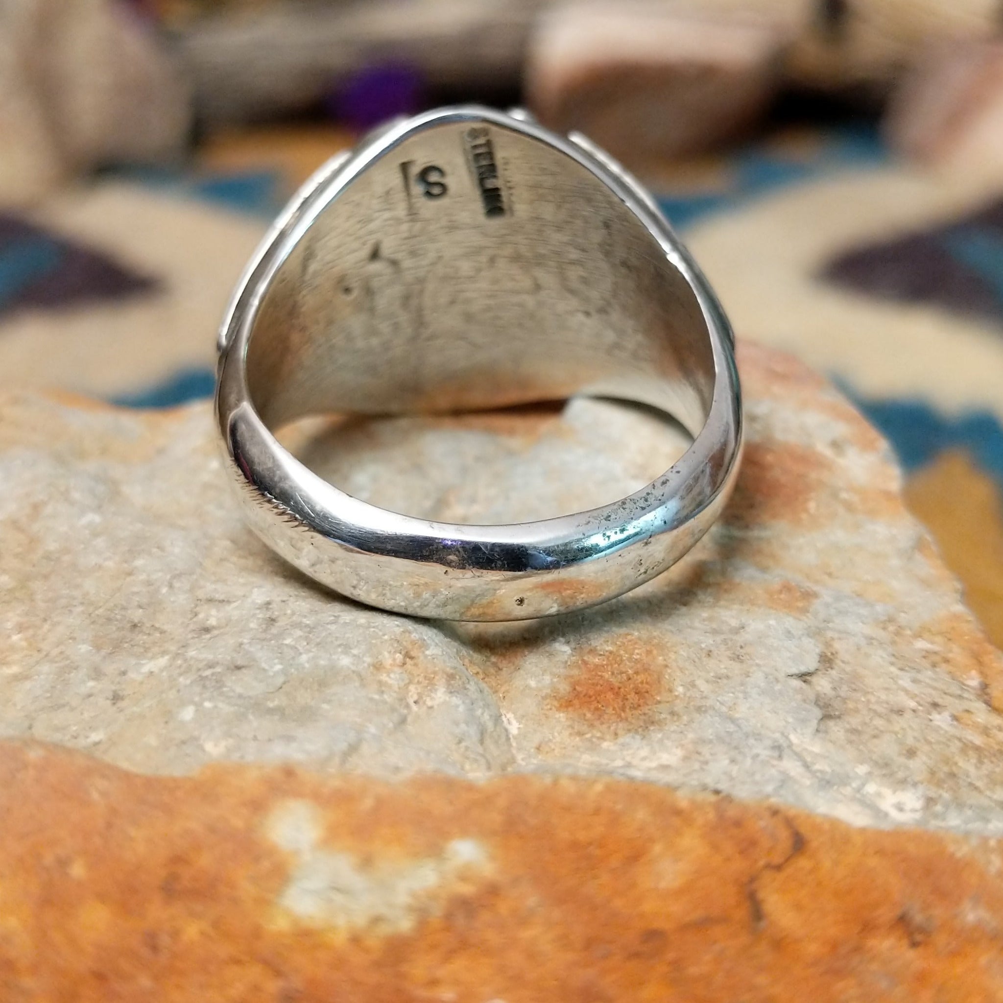 Handcrafted Navajo sterling silver ring featuring two natural red coral cabochons and one blue turquoise cabochon with traditional sawtooth bezels, silver raindrop accents, and a split-shank band; underside view.