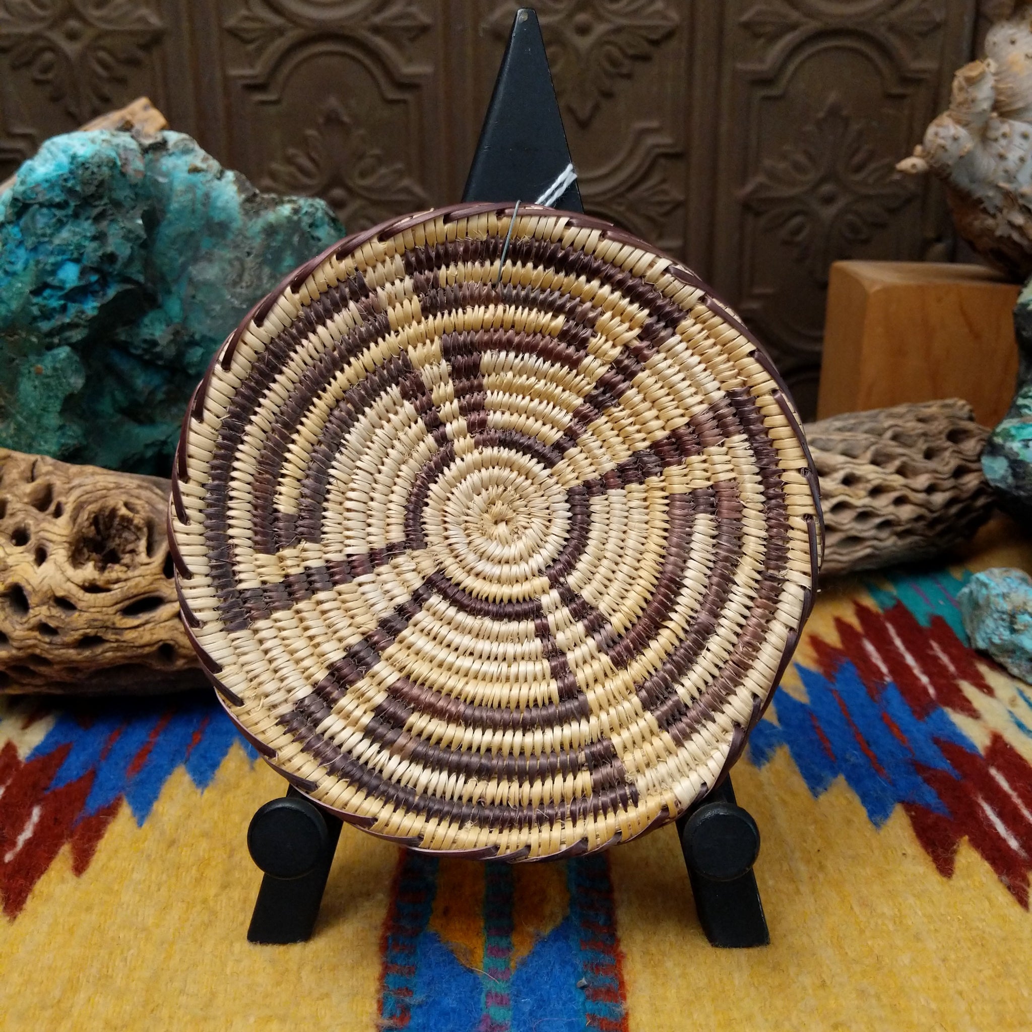 Navajo handwoven patterned basket by Louise with a geometric spiral design in natural and dark dyed fibers.