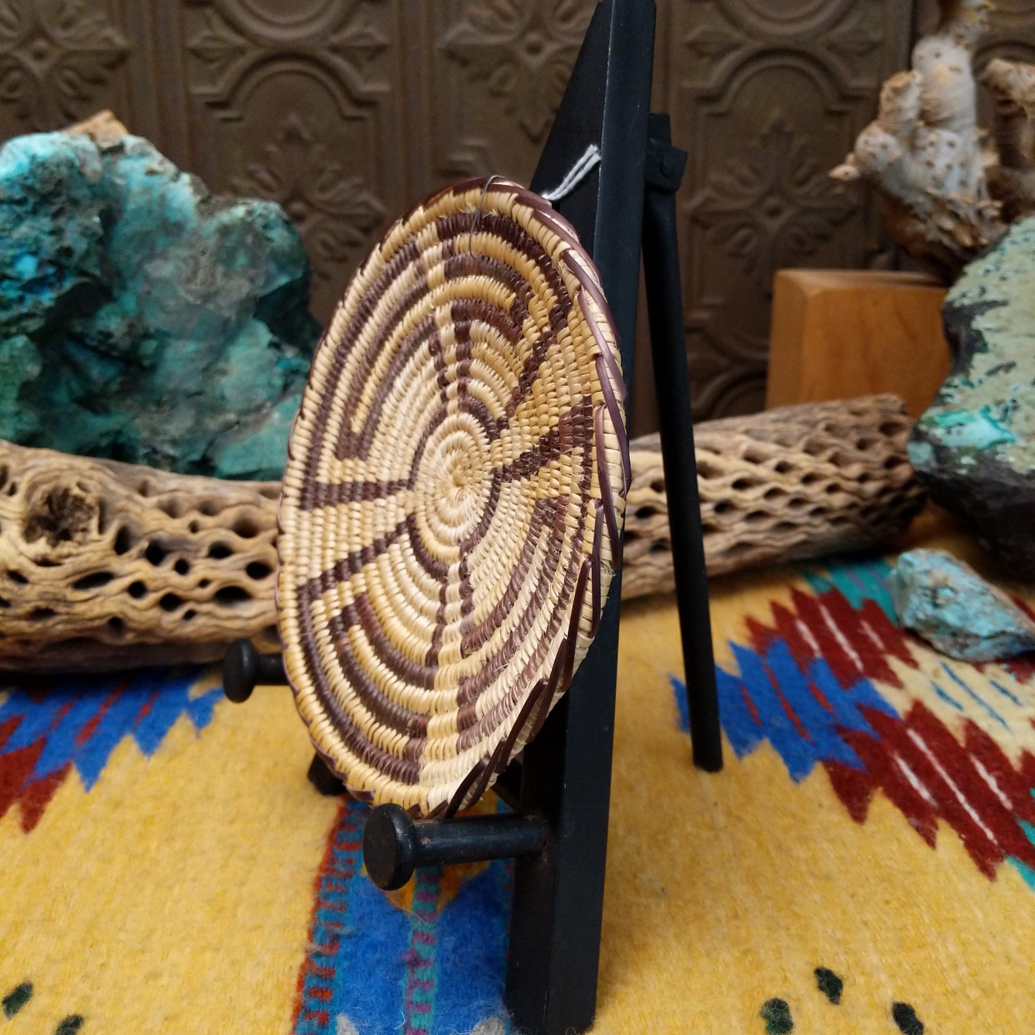 Navajo handwoven patterned basket by Louise with a geometric spiral design in natural and dark dyed fibers.