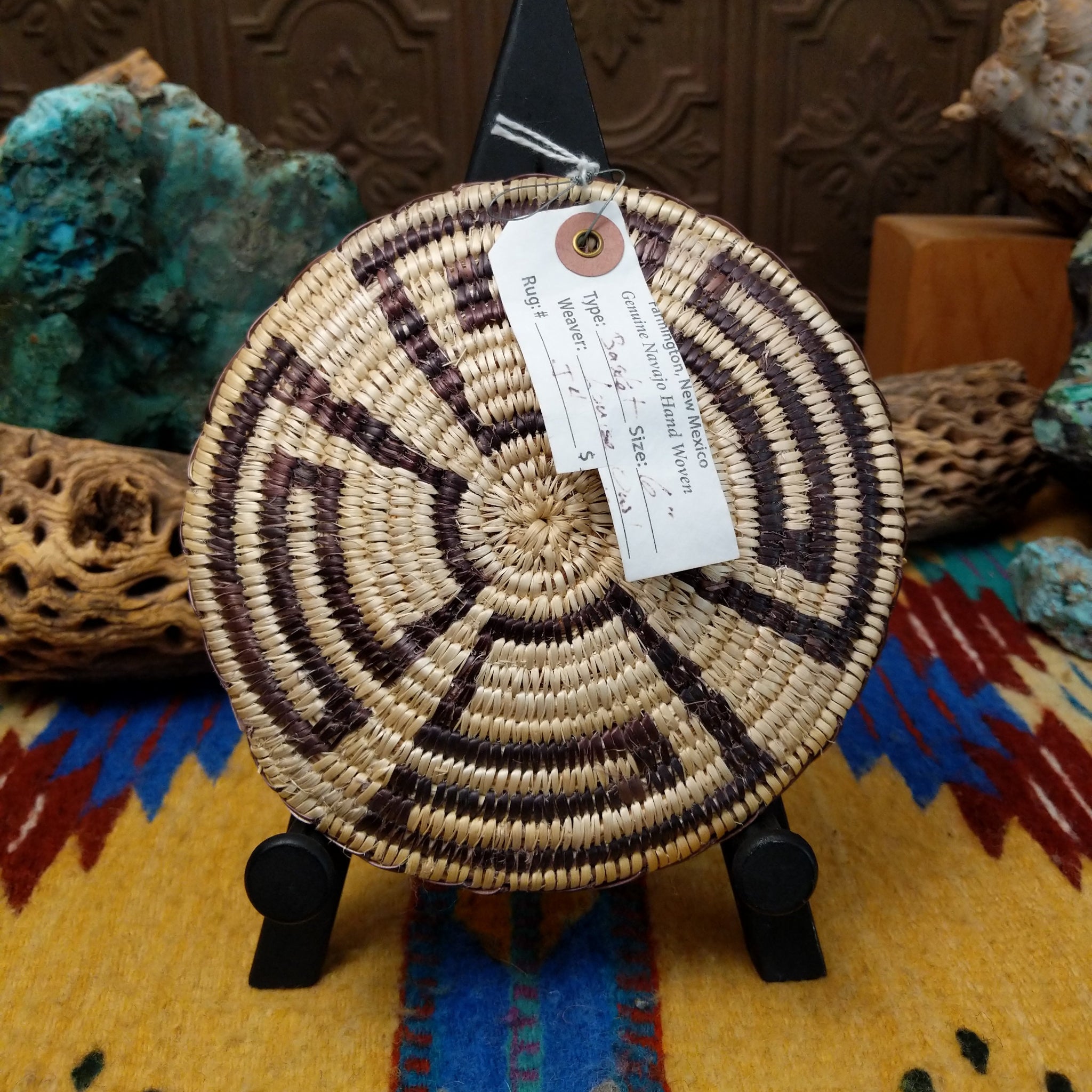 Navajo handwoven patterned basket by Louise with a geometric spiral design in natural and dark dyed fibers.
