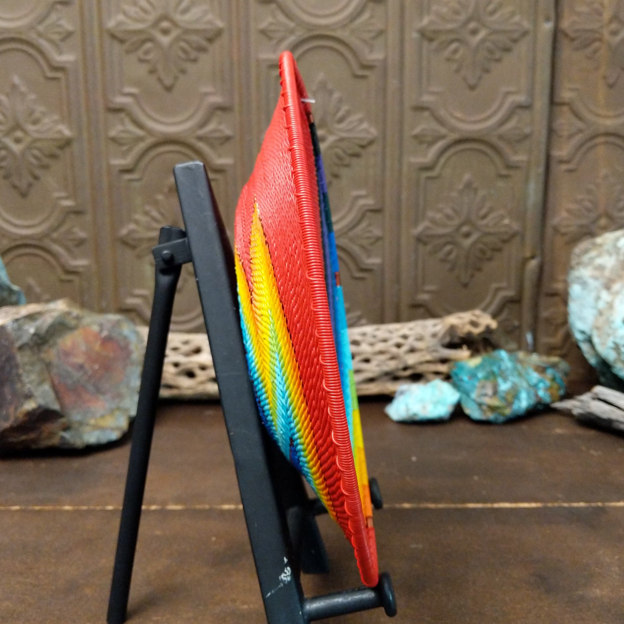 Handwoven rainbow wire art basket by Bridge for Africa featuring colorful recycled wire in a vibrant geometric pattern, ideal as a decorative bowl or wall display; side view.