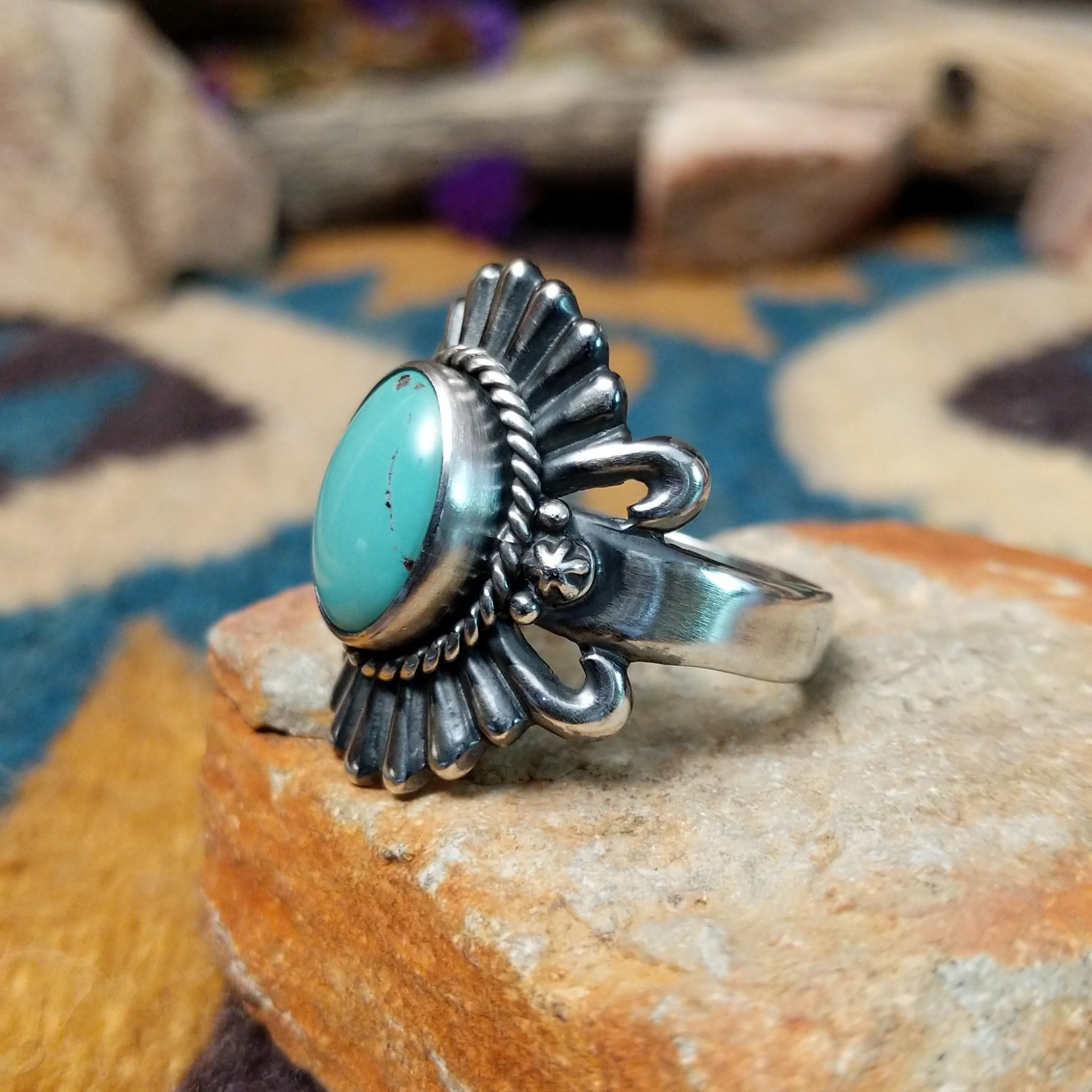Sterling silver turquoise ring by Raymond Coriz featuring an oval turquoise cabochon, twisted rope bezel, concho-inspired fan design, and intricate Southwestern silverwork; side view.