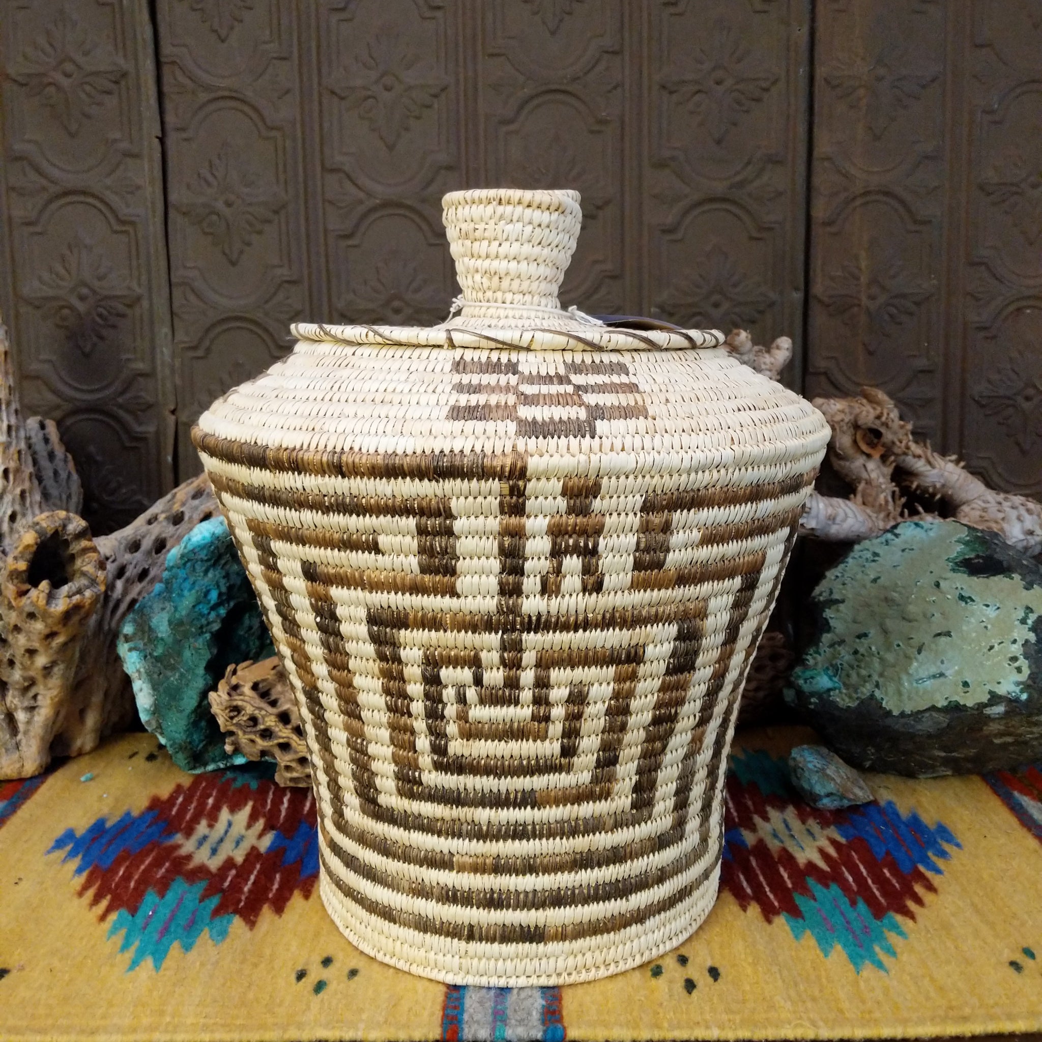 Award-winning Tohono O'odham handwoven lidded basket by Mary Thomas with geometric woven patterns in natural and dark fibers.
