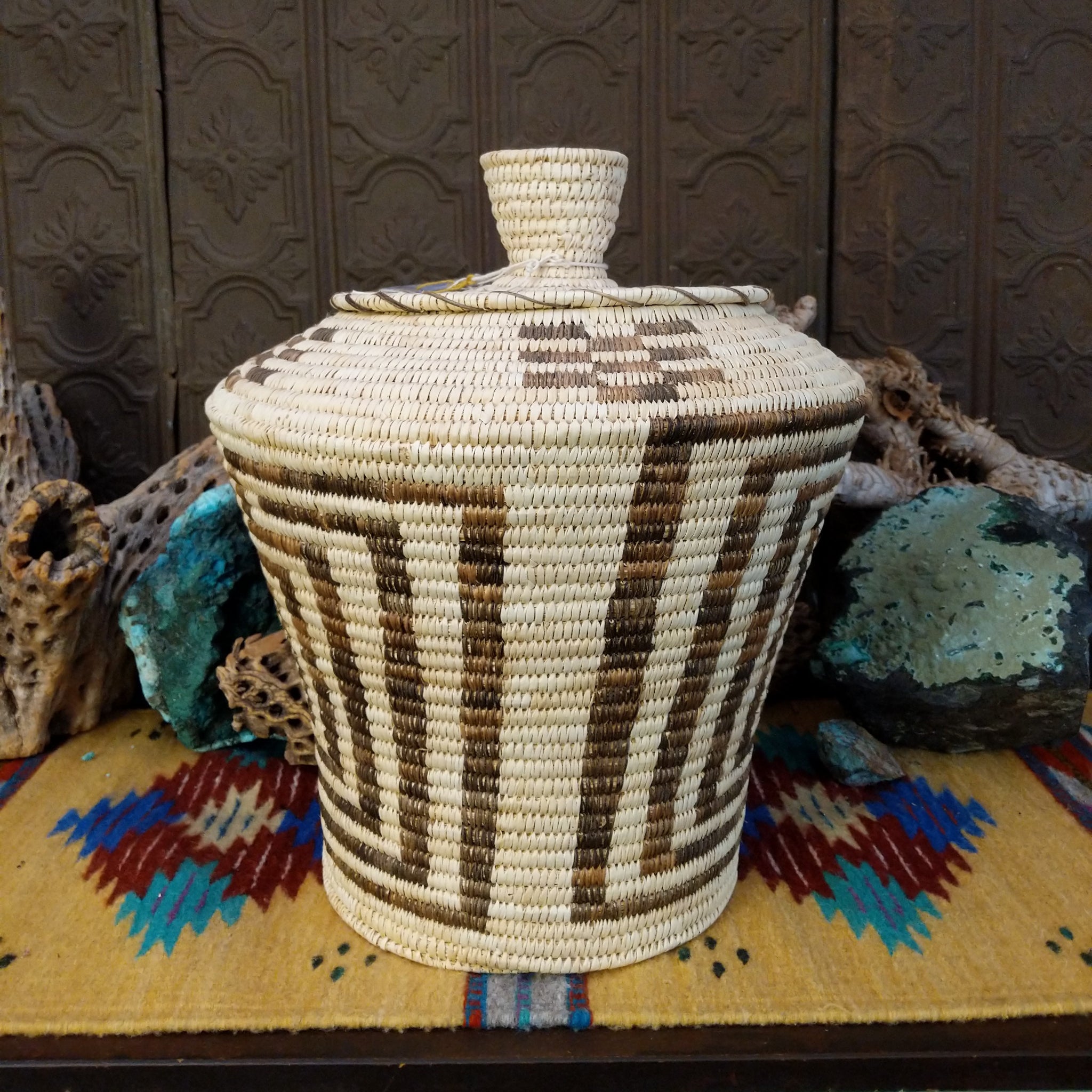 Award-winning Tohono O'odham handwoven lidded basket by Mary Thomas with geometric woven patterns in natural and dark fibers.