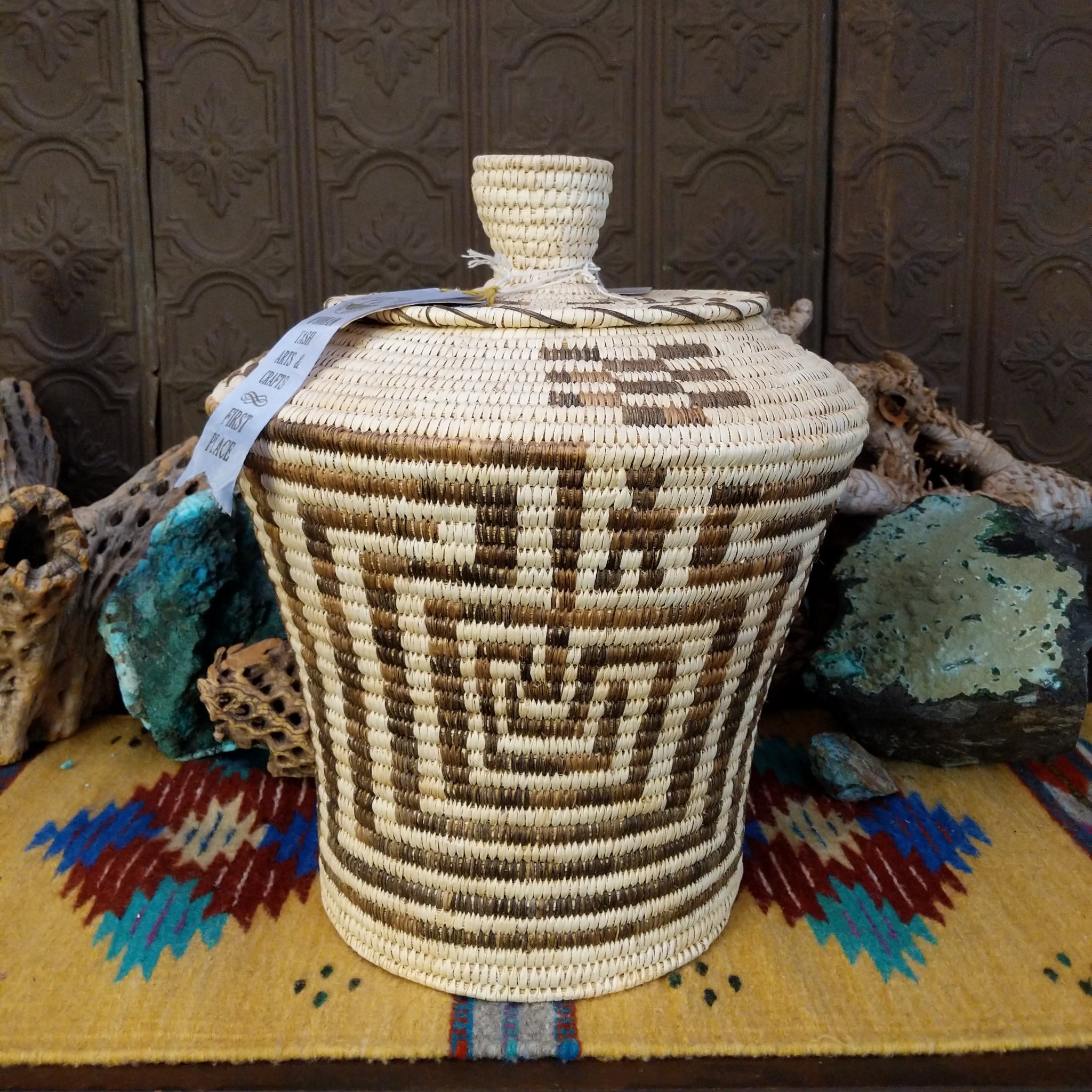 Award-winning Tohono O'odham handwoven lidded basket by Mary Thomas with geometric woven patterns in natural and dark fibers.