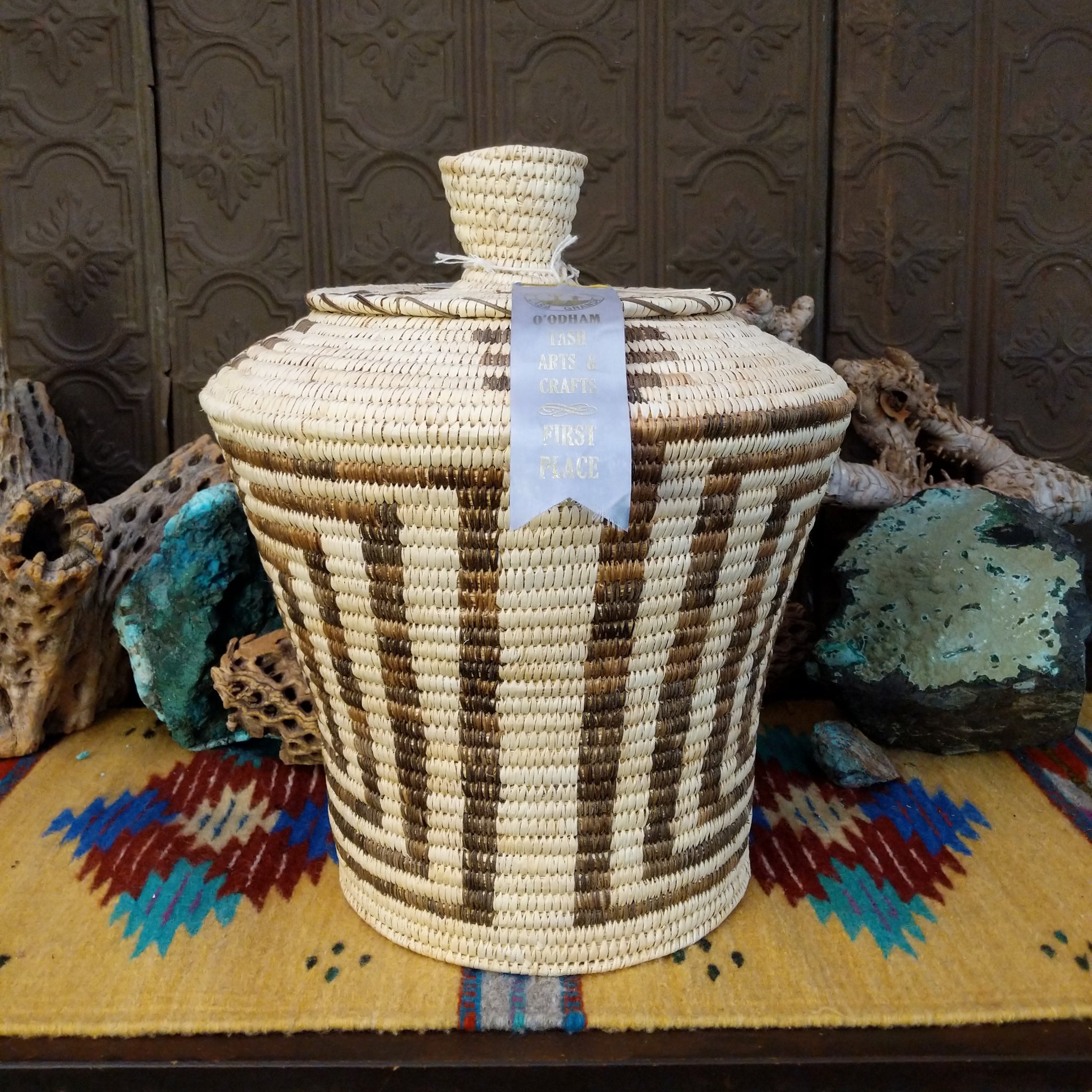 Award-winning Tohono O'odham handwoven lidded basket by Mary Thomas with geometric woven patterns in natural and dark fibers.