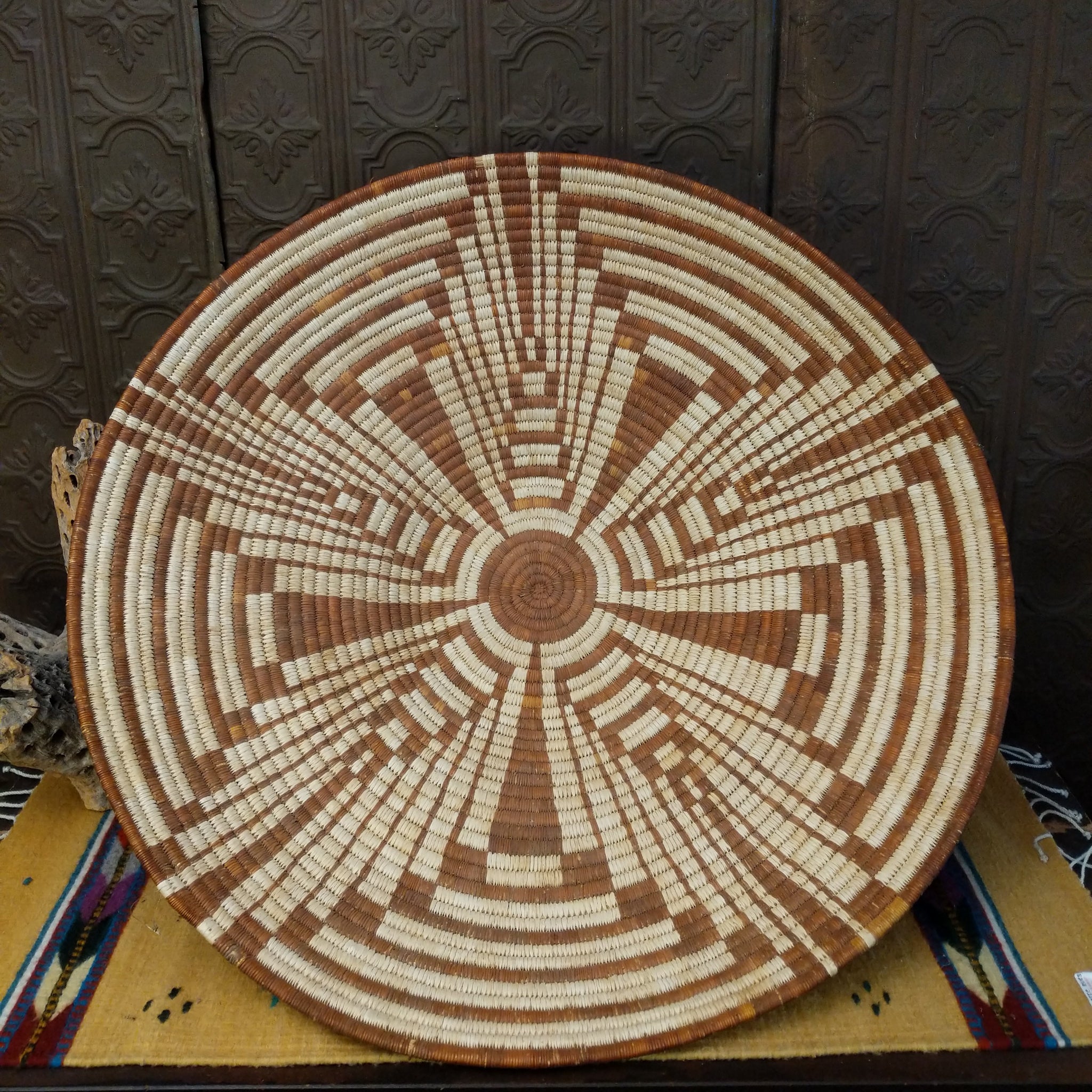 Large Tohono O'odham handwoven basket with a radiating geometric pattern in natural and reddish-brown fibers.