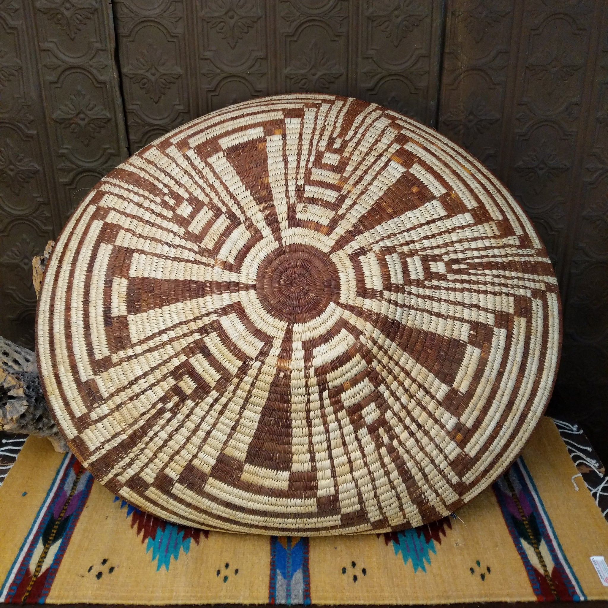 Large Tohono O'odham handwoven basket with a radiating geometric pattern in natural and reddish-brown fibers.